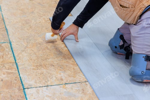 Preview: An installation worker installs vinyl laminate flooring in a new home