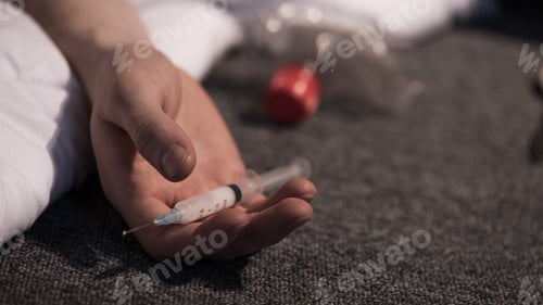Preview: selective focus of male hand with heroin dose in syringe