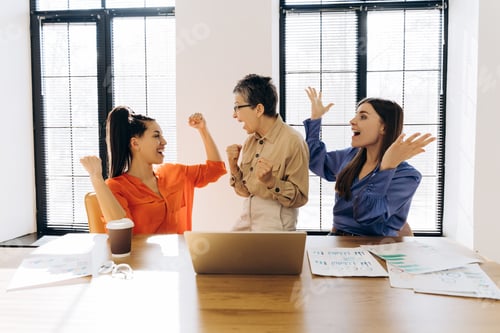 Preview: Excited businesswomen celebrating success in modern office