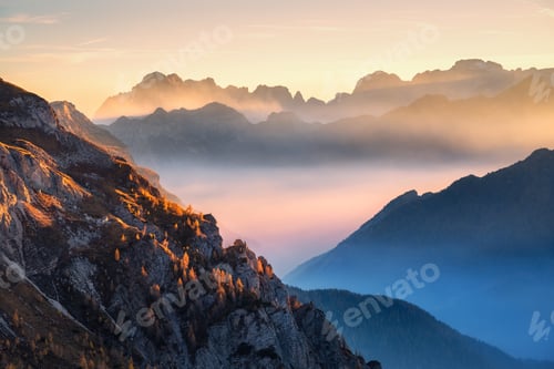Preview: Mountains in low clouds at beautiful sunset in autumn in Italy