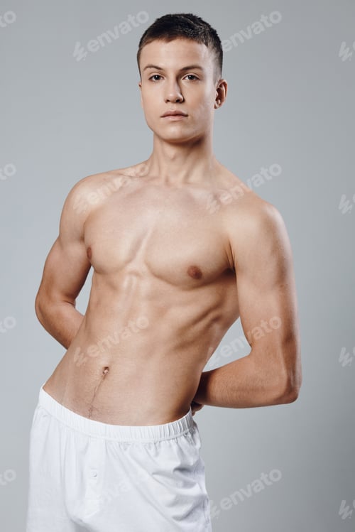 Preview: athlete with a pumped-up torso on a gray background holds his hands behind his back and white shorts