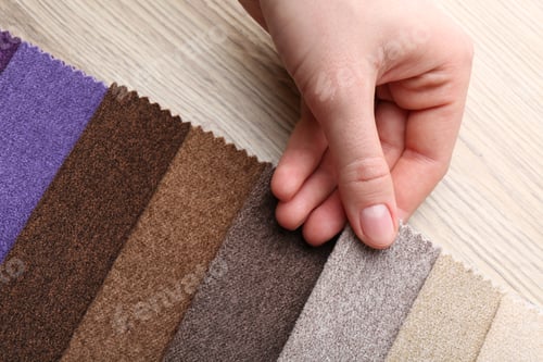 Preview: Woman with samples of different fabrics at wooden table, closeup