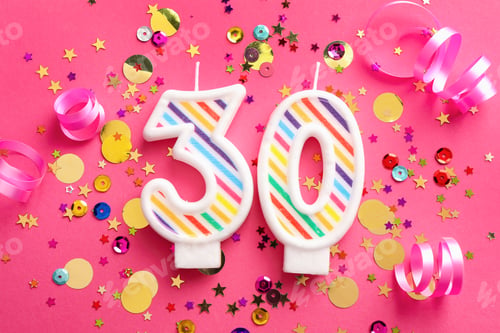 Vista previa: 30th birthday. Number shaped candles and confetti on pink background, flat lay