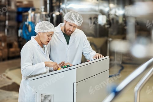 Preview: Two workers wearing lab coats operating equipment at food factory