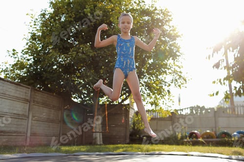 Preview: little sports girl jumps on a trampoline. Outdoor shot of girl jumping on trampoline, enjoys jumping