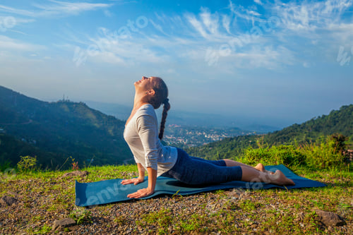 Preview: Woman practices yoga asana Urdhva Mukha Svanasana outdoors
