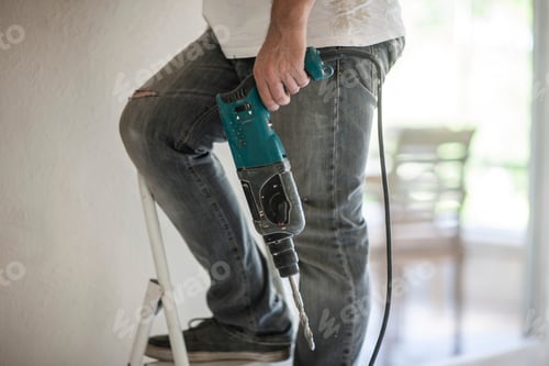 Preview: Builder holding drill on ladder