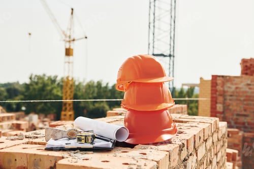 Preview: Crane is far away. Close up view of protective hard hats that laying down on the bricks
