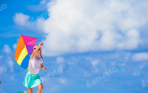 Preview: Little happy girl playing with flying kite on tropical beach