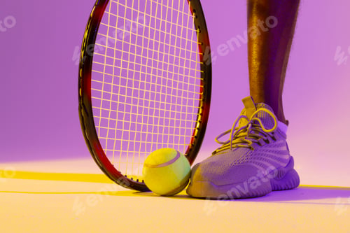 Preview: Image of leg of african american male tennis player in violet and yellow neon lighting