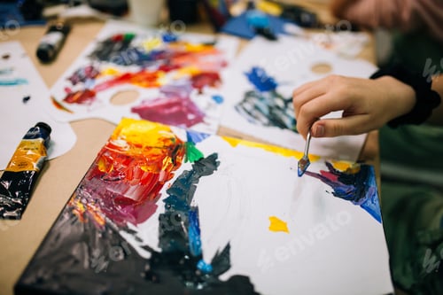 Preview: A man's hand paints a picture with a palette knife and bright acrylic paints