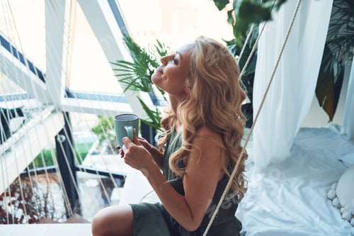 Preview: Woman Relaxing on Swing with Cup of Coffee