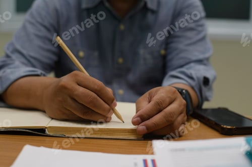 Preview: Man plan and noted schedule (holiday trip) in diary and using smartphone at office desk.