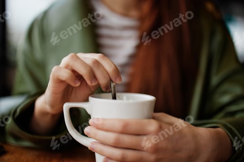 Preview: Woman in cafe stirring sugar in white coffee mug, autumn vibe and warmth