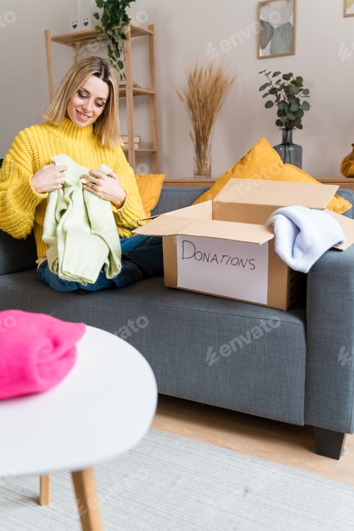 Preview: Happy woman packing clothes to donations