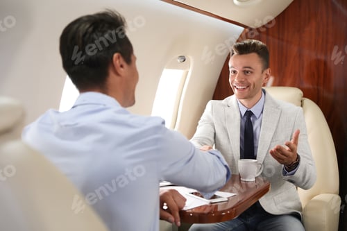 Preview: Young people shaking hands after bargaining on plane. Business deal