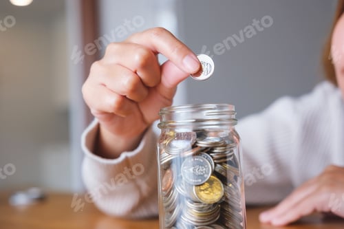 Preview: Woman Adding a Coin to Savings Jar