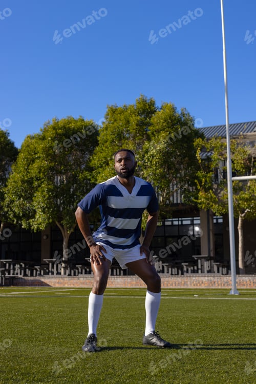 Preview: African American young male athlete standing on a rugby field outdoors, hands on hips