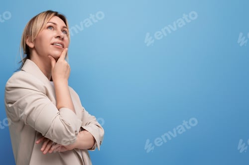 Preview: dreamy blonde young adult in beige jacket on studio background with copy space