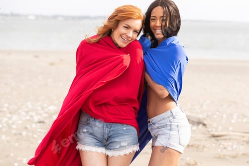 Preview: Two women playing with colorful fabric at the ocean beach