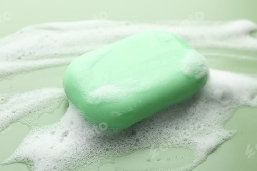 Preview: Soap bar with foam on green background, closeup