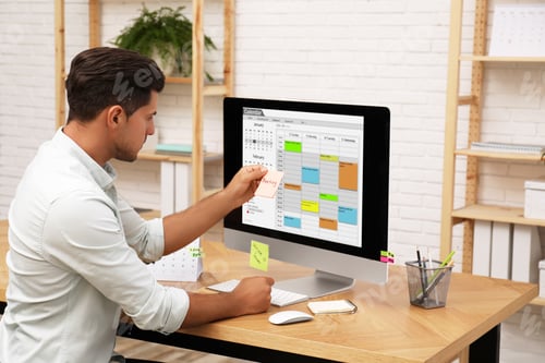 Preview: Handsome man using calendar app on computer in office