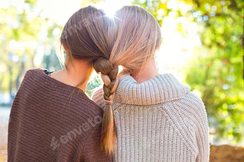 Preview: Fashionable beautiful young girlfriends with hairdress together in the autumn park