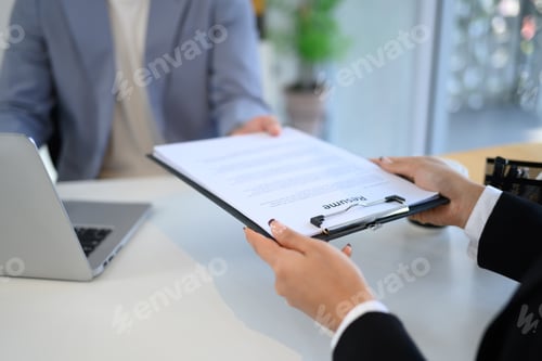 Preview: Close up of a candidate handing over resume to the interviewer during formal job interview