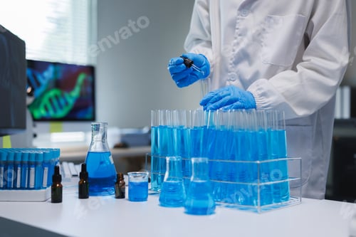 Preview: Scientist dropping blue liquid into test tubes