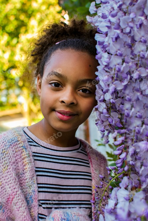 Preview: Portrait of Generation Z girl in front of purple wisteria flowers - petals pink mixed race diversity