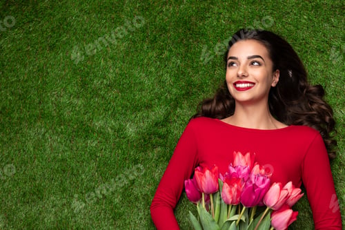 Preview: Young dreaming girl with flowers lying on meadow