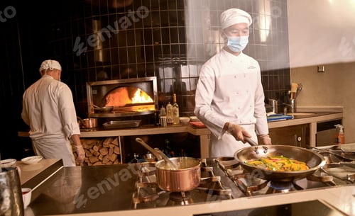 Preview: Asian cook keeping peppers in pan over stove burner