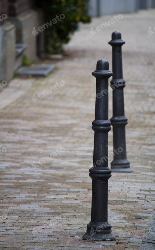 Preview: Closeup of black cast iron bollards installed in the middle of the street