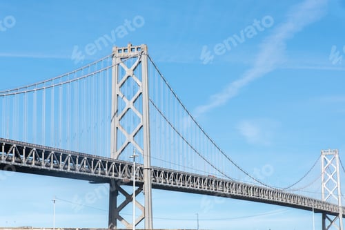 Preview: A large bridge spans a body of water, with a clear blue sky above