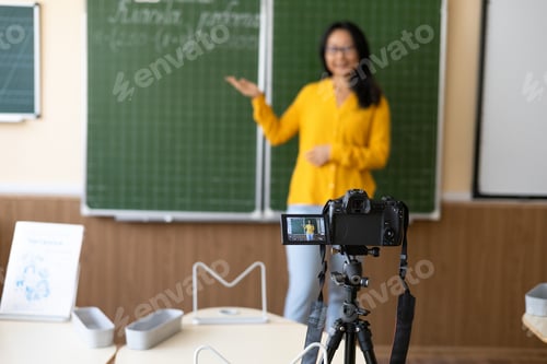 Preview: Modern education remotely. Cheerful young Asian woman pointing at the board and explaining math onli