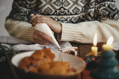 Preview: Hands decorating christmas gingerbread cookie star with icing on rustic table. Making cookies