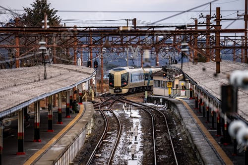 Preview: Train approaching a station with multiple tracks and platforms on a cloudy day