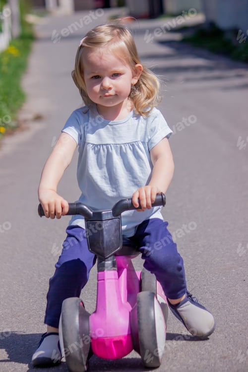 Preview: Little girl riding a balance bike. nature.