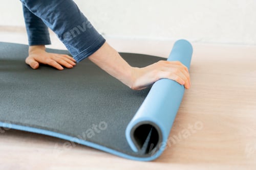 Preview: young man roll and lay the yoga sport matt on the wooden floor in the gym f