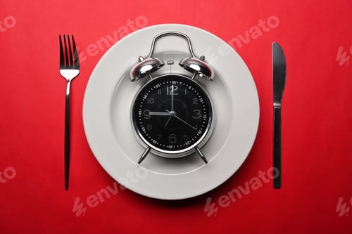 Preview: Alarm clock with knife and fork on red background. Meal planning for diet concept.