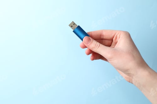 Preview: Woman holding USB flash drive on light blue background, closeup. Space for text