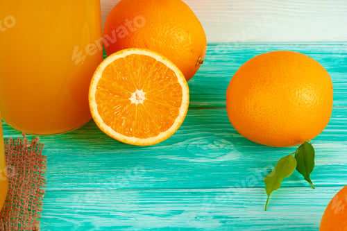Preview: Glass of orange juice and cut oranges on table