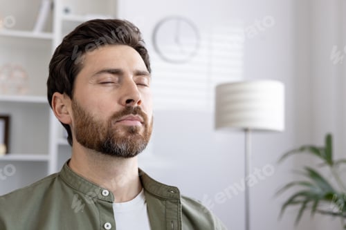 Preview: Calm man with closed eyes relaxing in peaceful home environment reflecting inner peace and