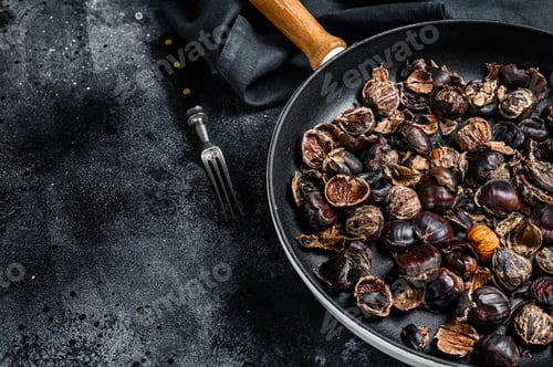 Preview: Roast grilled chestnuts on a wooden table. Black background. Top view. Copy space