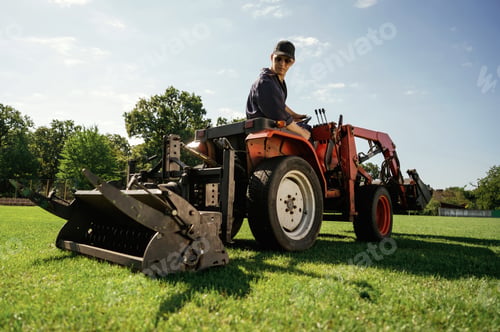 Preview: Loan work. Man is with utility tractor with grass cutter and aerator equipment on the field