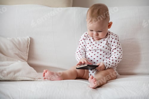 Preview: Baby girl sitting on white sofa and holding grey tablet