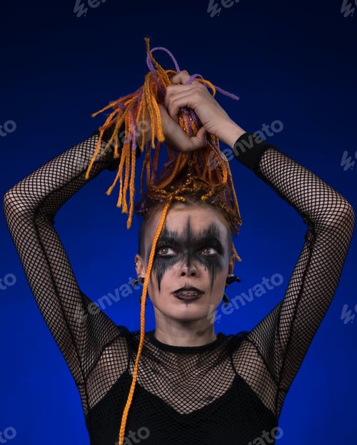 Preview: Informal young female with colored braids hairdo and spooky black stage makeup painted on face