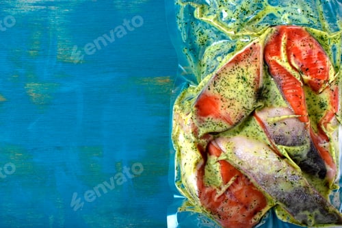 Preview: Vacuum packed pink salmon steaks in creamy sauce with herbs on blue background
