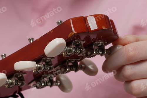 Preview: Extreme close-up of female fingers tuning acoustic guitar, tightening and loosening strings
