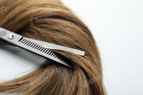 Preview: Beautiful hair strand and scissors on white background, closeup